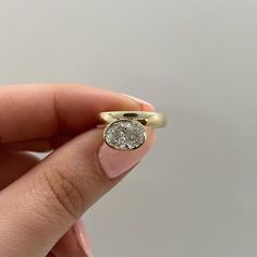 a woman's hand holding a yellow gold ring with a white diamond in it