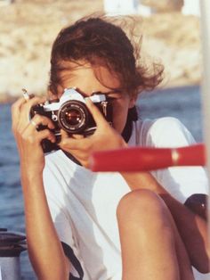 a person sitting on the ground with a camera in front of their face, taking pictures