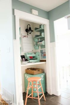 a small kitchen with blue walls and white trim on the cabinets, along with a bar stool