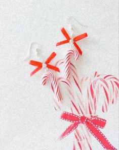 two candy canes with bows on them sitting next to each other in front of a white background