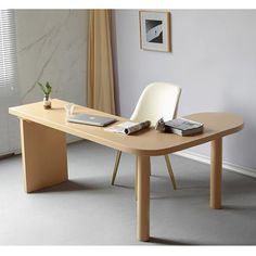 a table with a laptop and some books on it next to a chair in front of a window