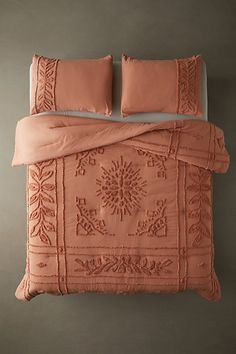 a bed with two pillows on top of it and an orange comforter in the middle