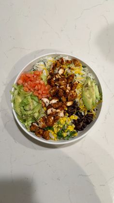 a white bowl filled with lots of different types of food on top of a table