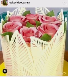 a white vase filled with pink roses on top of a table