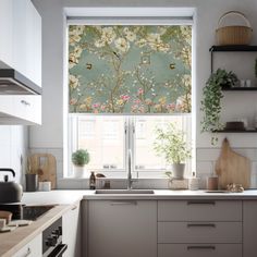 a kitchen with white cabinets and flowers on the window sill next to the sink