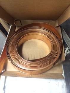 an open cardboard box filled with lots of copper colored metal tubes and wires in it