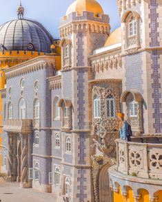 an elaborately designed building with yellow and blue tiles on the walls, in front of a domed dome