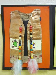 a paper bag with some beads and feathers hanging from it's side on a wall