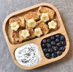 a wooden tray filled with blueberries, bananas and other foods on top of a table