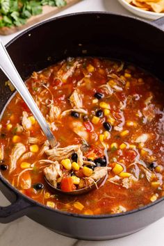 a bowl of chicken tortilla soup with a ladle full of the soup