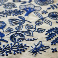 embroidered fabric with blue flowers and bugs on it's surface, closeup view