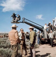 several men are standing in the dirt near a truck with a camera attached to it