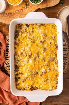 a casserole dish with meat and cheese in it sitting on a wooden table