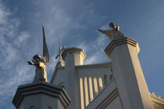 two statues on the top of a building with blue skies in the backround