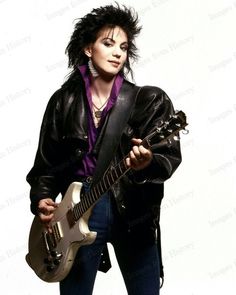 a woman with black hair holding a white guitar