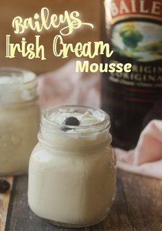 two jars filled with ice cream sitting on top of a wooden table next to a bottle of bailey's irish cream mousse