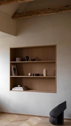 a book shelf in the corner of a room with wooden flooring and white walls