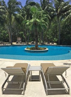 two lounge chairs next to an empty swimming pool