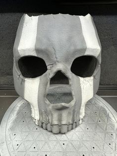 a fake skull sitting on top of a metal plate with holes in it's face