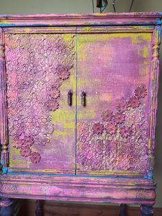 an old purple painted cabinet with flowers on it