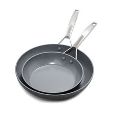 two stainless steel pans with tongs in them sitting side by side on a white surface