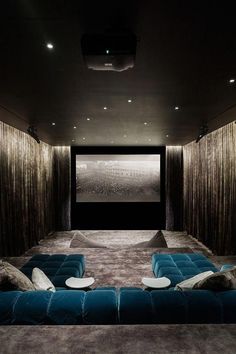 a home theater with blue velvet couches and large screen in the middle of the room