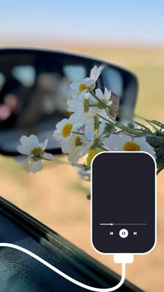 a flower is plugged in to a car's rear view mirror with an mp3 player attached