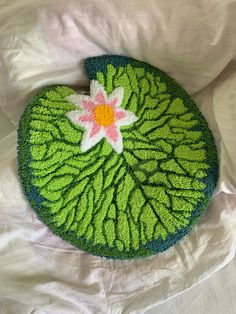 a crocheted green leaf with a pink flower on it