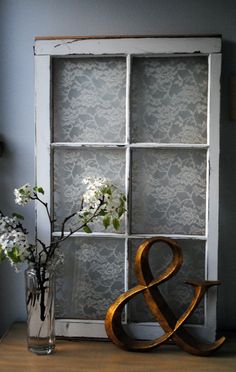 a vase with flowers sitting next to an old window frame and decorative sign that says & amp