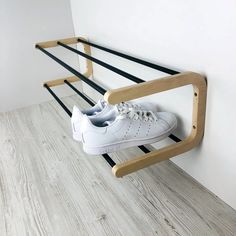 a pair of white shoes are hanging on a wooden shoe rack