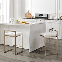 a kitchen with white cabinets and marble countertops, two stools are in front of the island