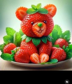 a teddy bear made out of strawberries sitting on top of a plate with green leaves