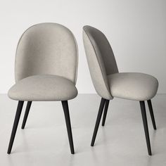 two gray chairs sitting next to each other on top of a white floor with black legs