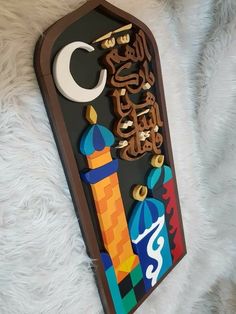 a wooden sign with arabic writing on it and a crescent in the middle, sitting on a white furnishing