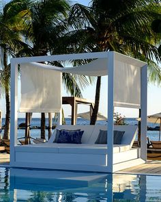 a bed sitting on top of a swimming pool next to palm trees and the ocean