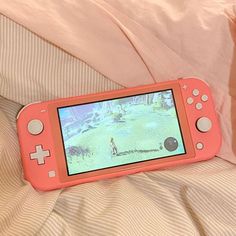 an orange nintendo wii game system sitting on top of a bed next to a pink comforter