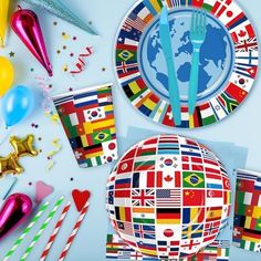 the table is set with flags and balloons for an international celebration, including forks and spoons