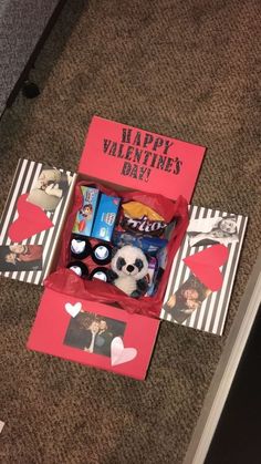 an open valentine's day box on the floor with pictures and candies in it