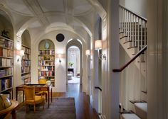 the hallway is lined with bookshelves and chairs, along with an arched doorway