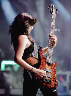 a woman holding a bass guitar on stage