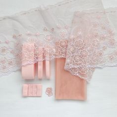 an assortment of pink garters and accessories laid out on a white tablecloth