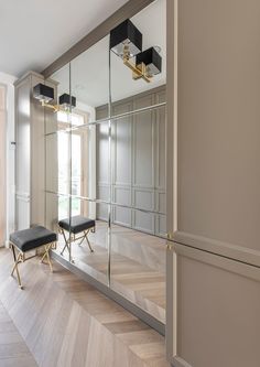 an empty room with mirrored walls and wooden flooring, along with a bench in the middle