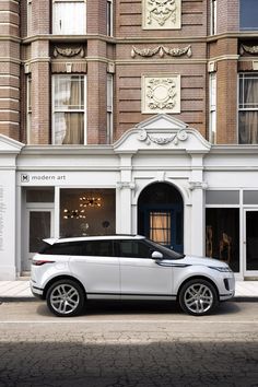 a white range rover parked in front of a building