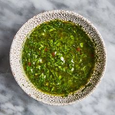 a bowl filled with green sauce on top of a table