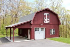 a large red barn with a white door and windows on the side of it, surrounded by trees