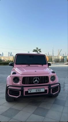 a pink mercedes g - class is parked on the street