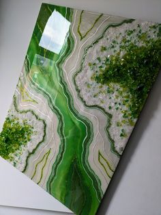 a piece of art with green and white designs on the wall next to a window