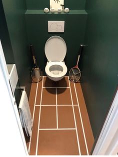 there is a toilet in the bathroom with green walls and brown tile on the floor