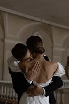 a bride and groom embrace in front of the staircase