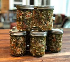 six jars filled with food sitting on top of a wooden table